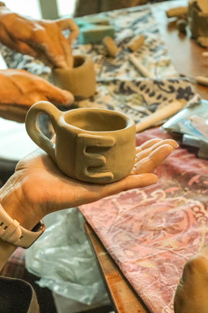 A detailed ceramic mug being crafted by hand in a pottery workshop.